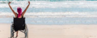 Mujer en silla de ruedas festejando frente a la playa